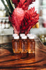 Six bottles of local honey in front of tropical flowers